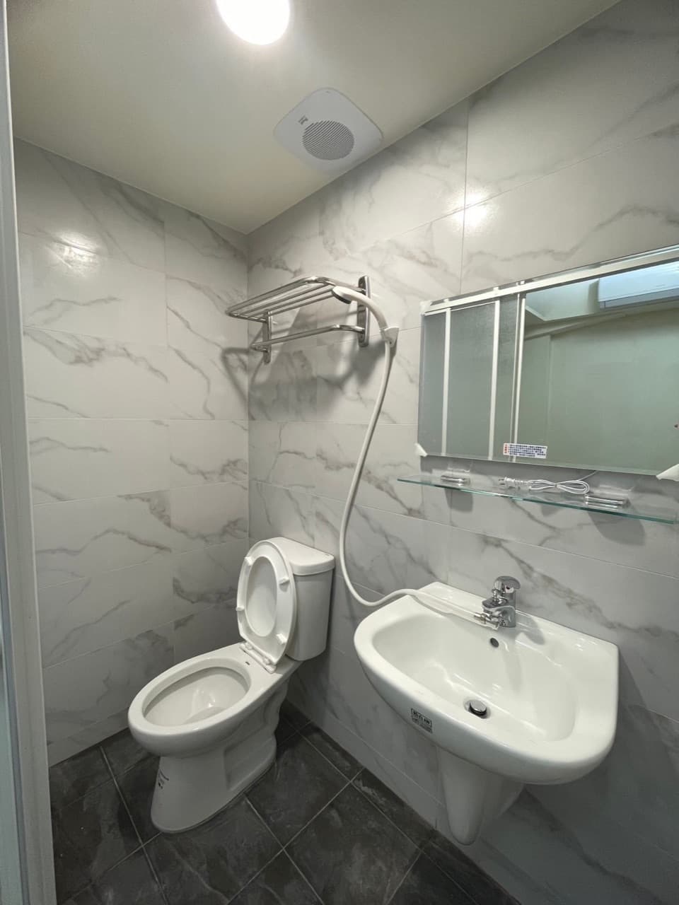 Newly tiled private bathroom with toilet, sink and shower