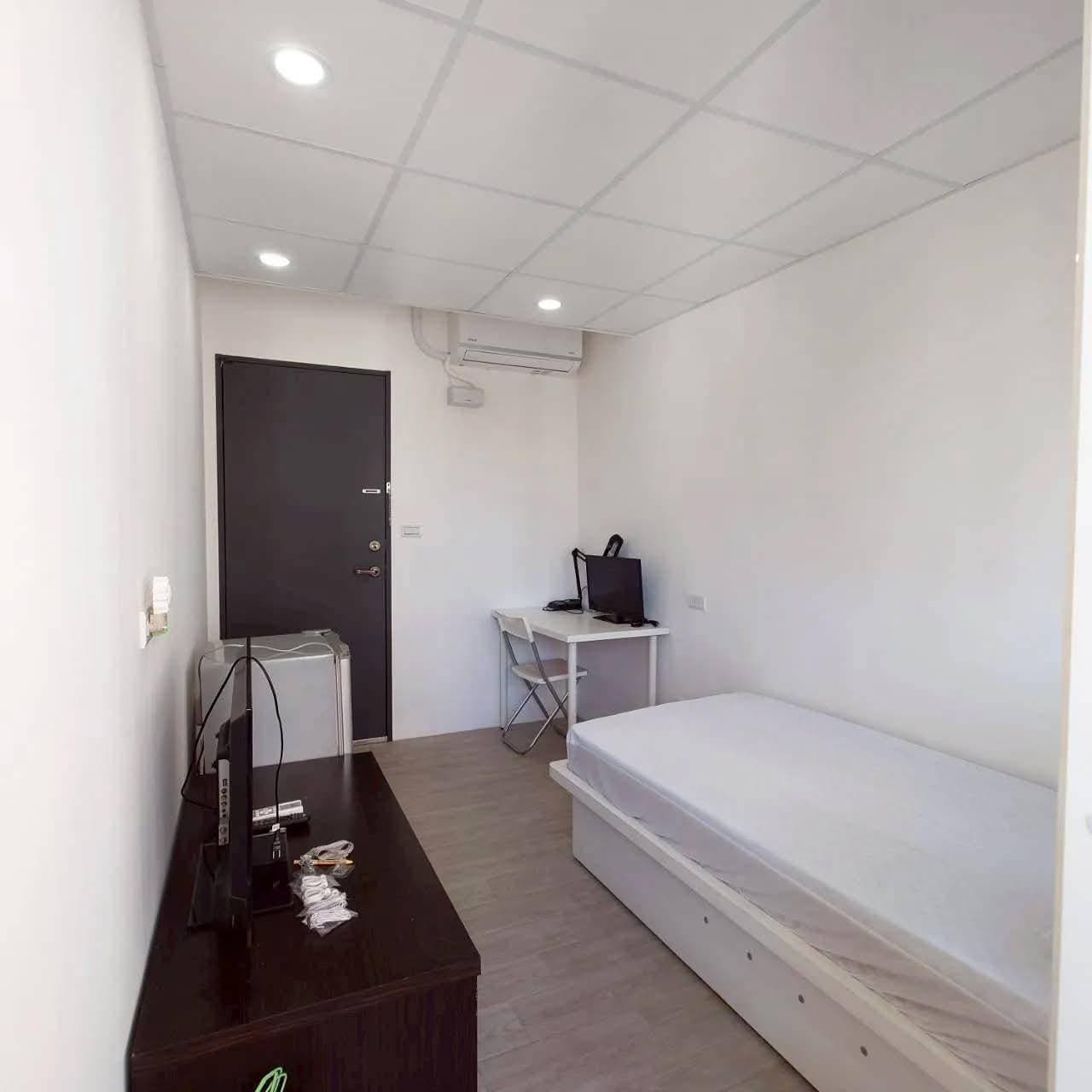Room seen from the window side, with desk, air conditioner and entrance door